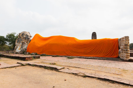 Ancient reclining lion statue adorned with vibrant orange drapery showcasing rich historical significance.の写真素材