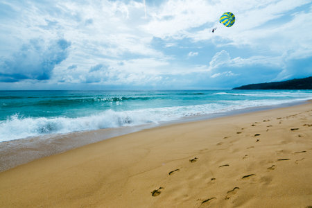 Experience the thrill of parasailing over a picturesque beach with stunning ocean views.の写真素材