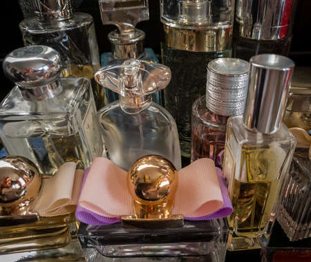 A close up view of a selection of perfume glass bottles in a group with a dark background.の写真素材