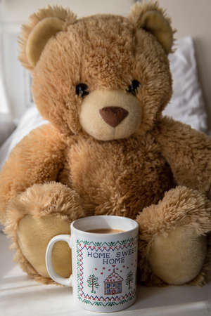 A teddy bear with a mug of milk tea in front. Home comfort concept.の写真素材