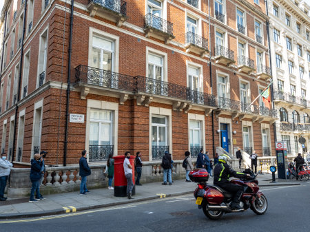 London. UK. 03.31.2021. Exterior view of the Consulate General of Portugal in Marylebone with a long queue of people outside waiting for its services.のeditorial素材