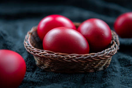 A closeup of Easter eggs in a wicker basket dyed in the traditional red colour.の写真素材