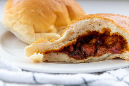 A closeup of baked char siu bao or BBQ pork buns showing the meaty filling inside.