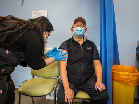 London. UK- 05.17.2021: a matured man getting an injection on the right arm of Covid-19 vaccine in a...