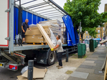 London. UK- 08.13.2021: workers unloading heavy packages off a heavy goods vehicle.