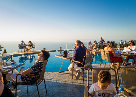 Lefkada island. Greece- -8.-7.2021: people and tourists enjoying pool side fine dining with amazing view.のeditorial素材