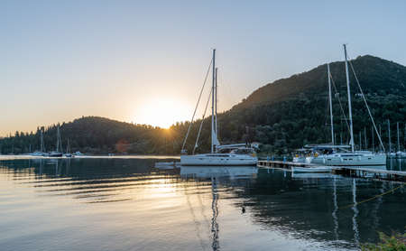 Sunrise over calm sea with sailing yachts.の写真素材