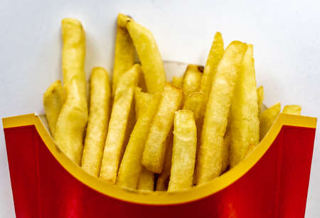 Close up of a portion of golden potato fries isolated in white.