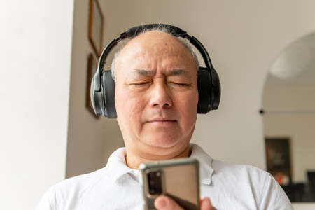 A man enjoying online music listening with a pair of headphones.