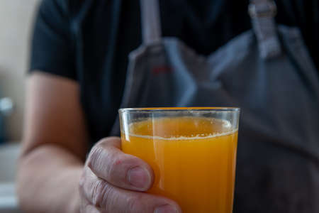 A person holding a glass of freshly squeezed orange juice.の写真素材