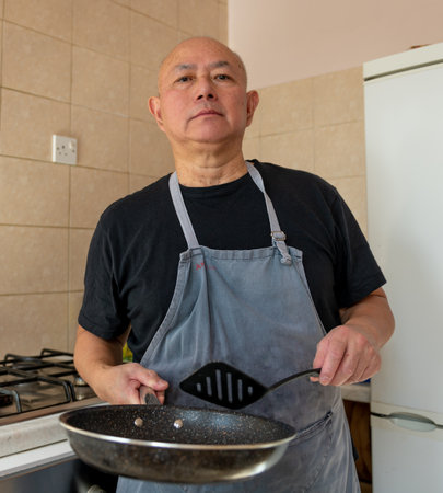 Portrait of a senior man, cook, making a meal in the kitchen.の写真素材