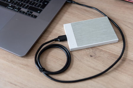 A external hard drive, file storage device connected to a laptop computer.