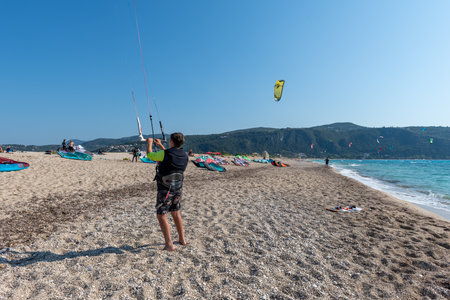 Lefkada island. Greece- 06.21.2023. A gathering of Kitesurfing people with some relaxing on the long sandy beach and some surfing in the sea.のeditorial素材