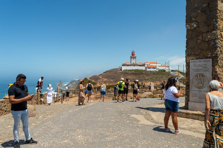 Cape Roca. Portugal- 07.08.2023. Tourists at the monument marking the wester most point of continental Europe with the lighthouse in the background.のeditorial素材