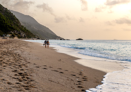 A couple on holiday walking on a beautiful long sandy beach.の写真素材