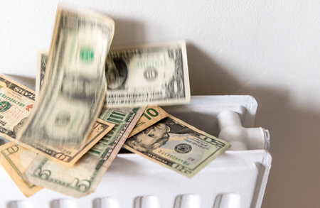 A heating, energy cost concept with a pile of US Dollars rising from a central heating radiator.の写真素材