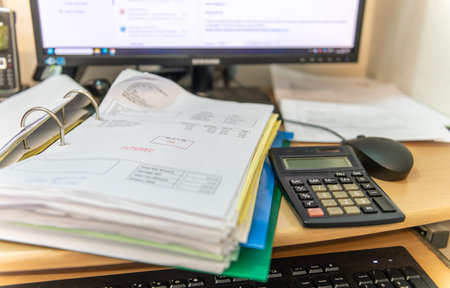A business work station with a folder of invoices, desk top computer, keyboard, mouse and calculator. Business accounting concept.の写真素材