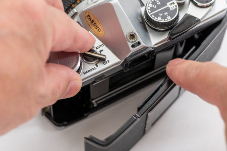 Close up of a person opening the back cover for inserting the film roll into a vintage SLR photo camera.の写真素材