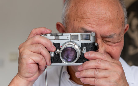 A senior man using a classic vintage camera to take photos.の写真素材
