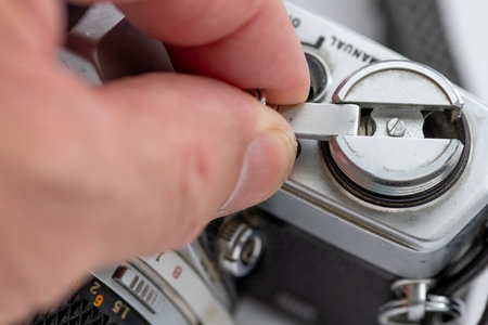 Close up of a person using the film roll rewind lever of a vintage SLR photo camera.の写真素材