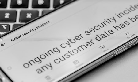 Close up of a message on a mobile phone from a company informing its clients of an ongoing cyber security incident.の写真素材