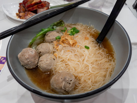 A delicious bowl of rice vermicelli soup with beef meat balls and greens.
