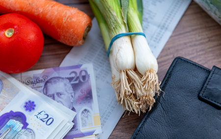 A UK cost of living concept with Sterling bank notes, a grocery receipt, purse and some groceries.