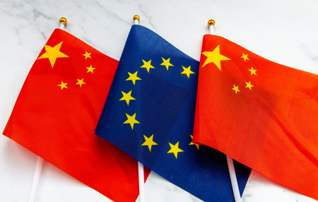 The European Union flag on flag pole in between the Chinese national flag. A EU, China relations concept.の写真素材