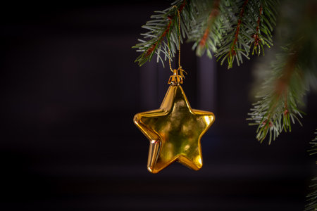 A closeup of a golden star shaped ornament hanging on a Christmas tree on a dark background. A Christmas elements, decorations background.の写真素材