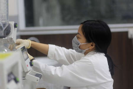 Vietnamese woman scientist operating a rotary evaporator to make an experiment in the laboratoryの写真素材