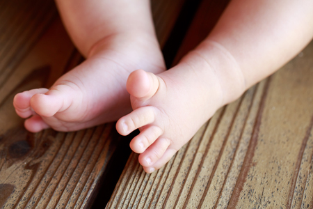 Little naked baby's legs on the benchの写真素材