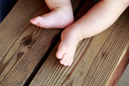 Little naked baby's legs on the benchの写真素材