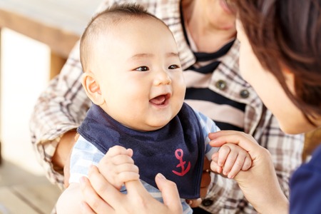 Happy together - smiling baby with his mother and his grandmother outdoorの写真素材