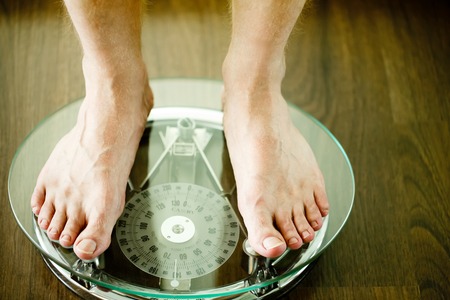 Male on standing on glass floor weight scales on wooden background, close upの写真素材