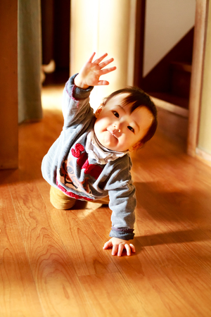 Beautiful baby boy crawling on the floor. and he raise his hand.の写真素材
