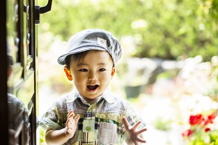 child boy put on a cap is surprised. Handsome happy child, isolated on green background.の写真素材