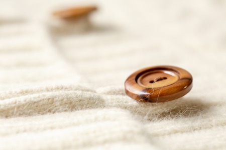 Beautiful, luxurious, white knit cardigan with wooden button. Close up.