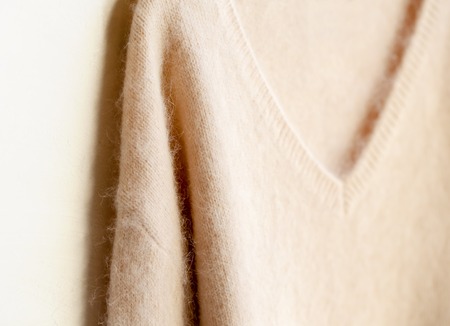 light pink sweater hanging on clothes hanger on white background.close up.の写真素材