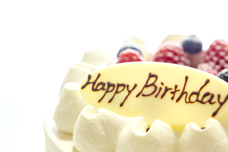 White cake decorated with strawberries and blueberries placed on a tray on a white table. Happy Birthdayの写真素材
