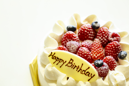 White cake decorated with strawberries and blueberries placed on a tray on a white table. Happy Birthdayの写真素材