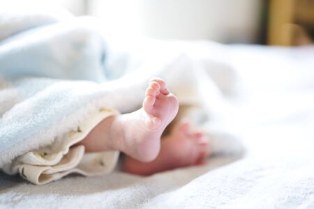 Newborn baby on a white and light blue blanket - tiny baby feet closeup.の写真素材