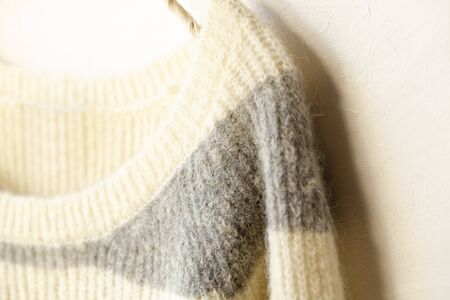 White and gray striped sweater hanging on clothes hanger on white background.close up.