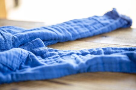 The blue pants thrown off on the wooden table and copy space.の写真素材