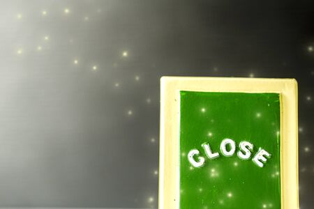 Close up of a green ,yellow with white "CLOSE" chalkboard sign leaning against sparkle ,bright with black background.の写真素材