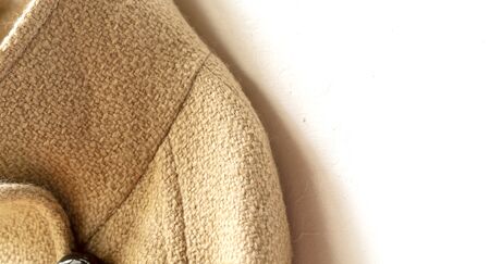 beige wool coat hanging on clothes hanger on white background.Close up.