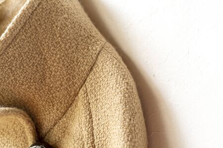 beige wool coat hanging on clothes hanger on white background.Close up.の写真素材