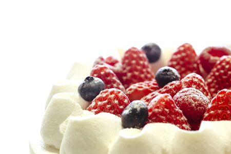 White cake decorated with strawberries and blueberries placed on a tray on a white table. close up.の写真素材