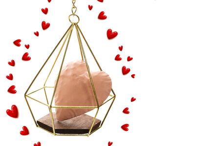 The pink heart enter the gold cage wrapped in red small hearts on white background and copy space.の写真素材