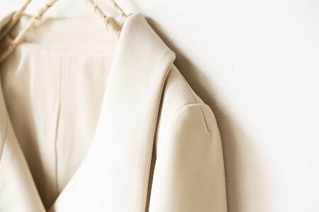 beige or white jacket hanging on clothes hanger on white background.close up.の写真素材