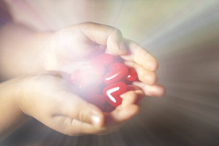 Little child holding red heart to give off light , close-up isolated on black gradation and copy space.の写真素材